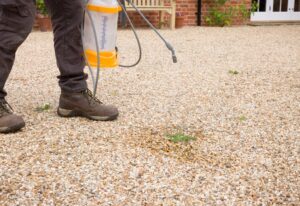 Person using weed control spray on gravel yard in Tracy, CA.